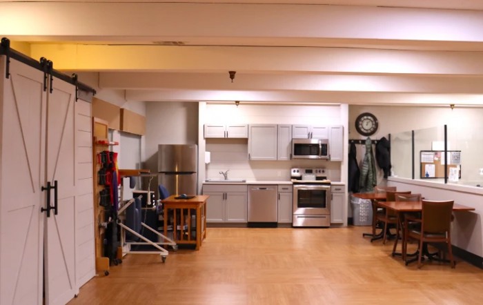 A modern apartment kitchen with stainless steel appliances and wooden flooring.