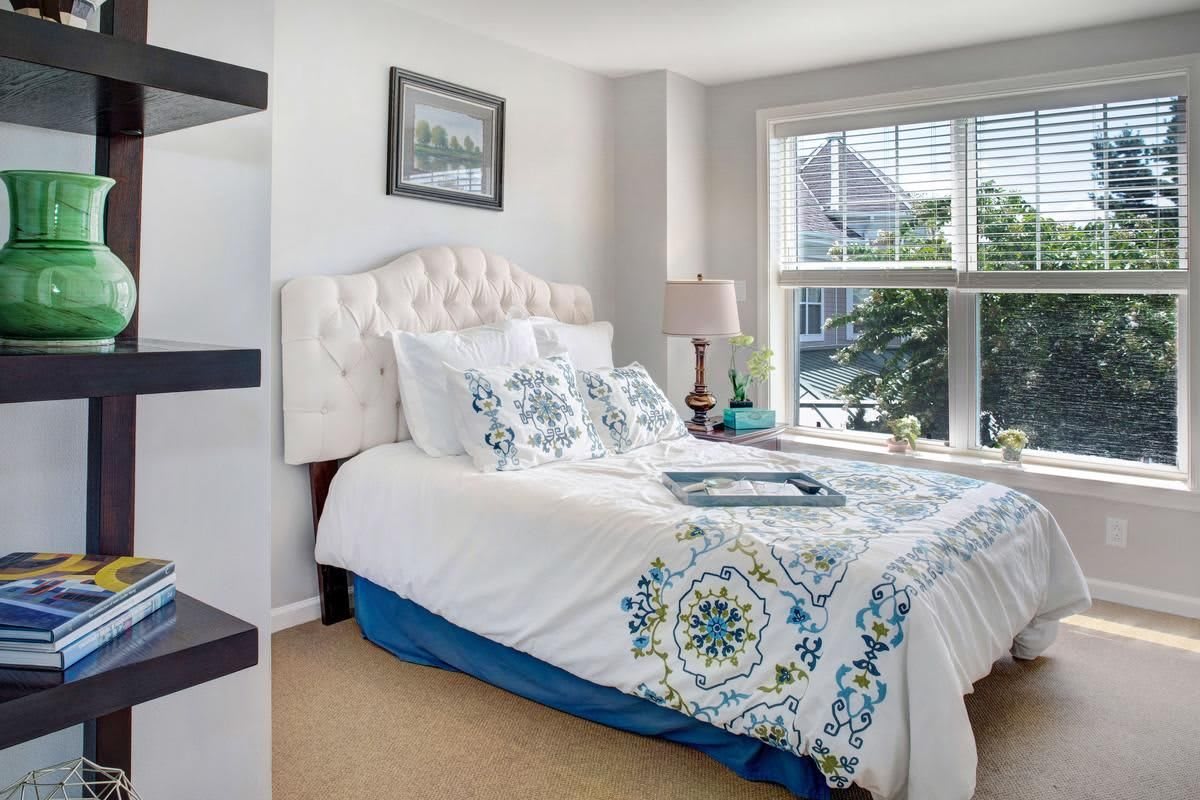 A cozy bedroom with elegant bedding and a large window letting in natural light.