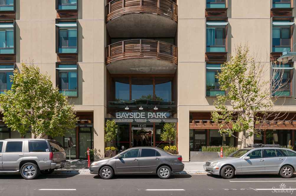 An urban building with a prominent entrance and parked cars along the city street.