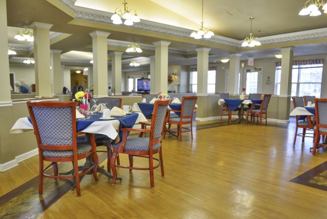 Spacious dining area with neatly arranged tables and chairs, featuring elegant lighting.