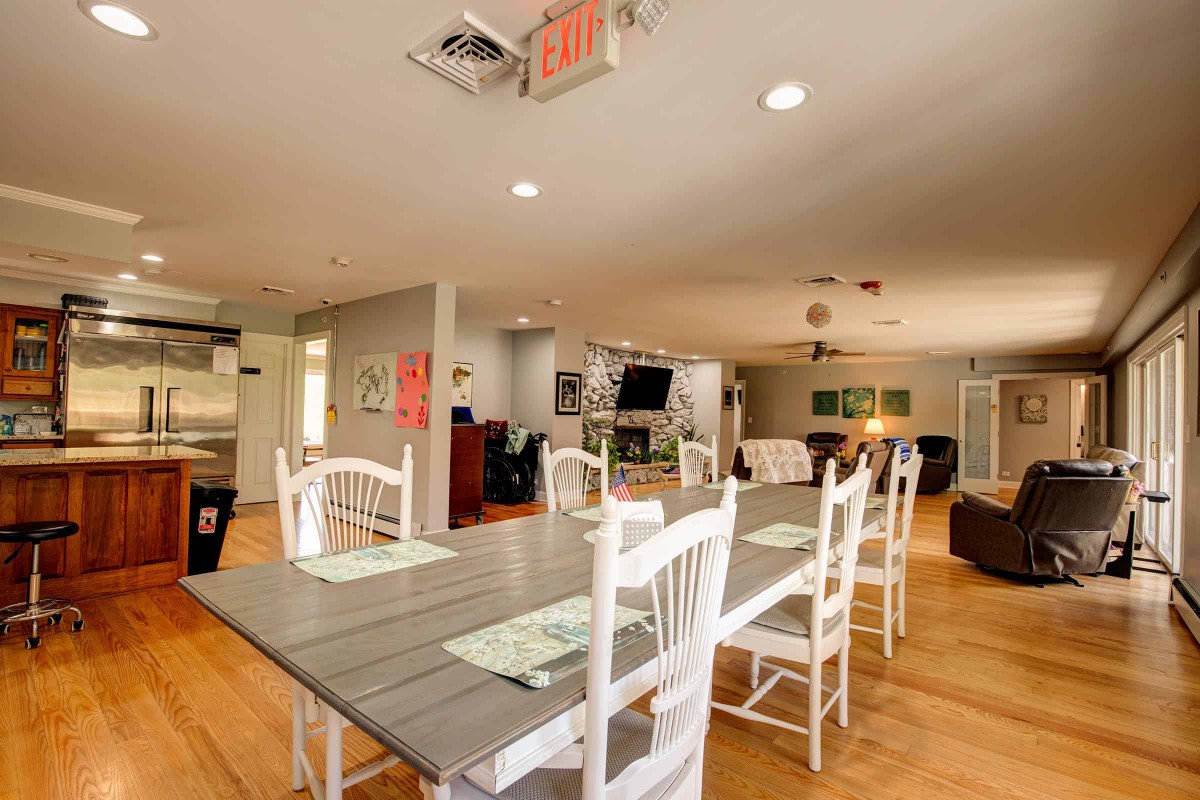 A spacious dining area with a wooden table and chairs, featuring an open kitchen layout.