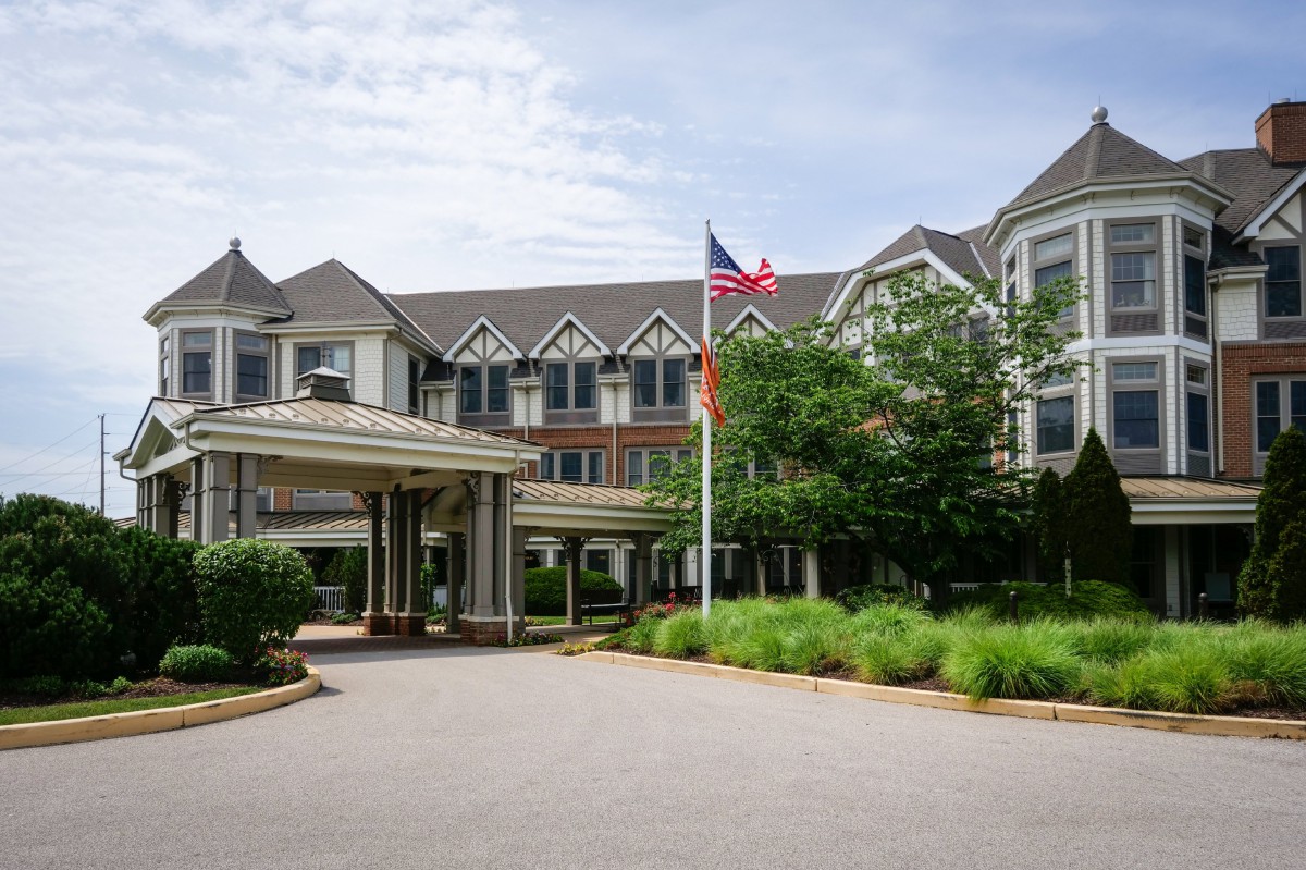 A hotel entrance with well-maintained landscaping and an American flag.