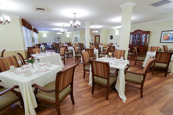 A spacious dining area with elegantly set tables and comfortable chairs.