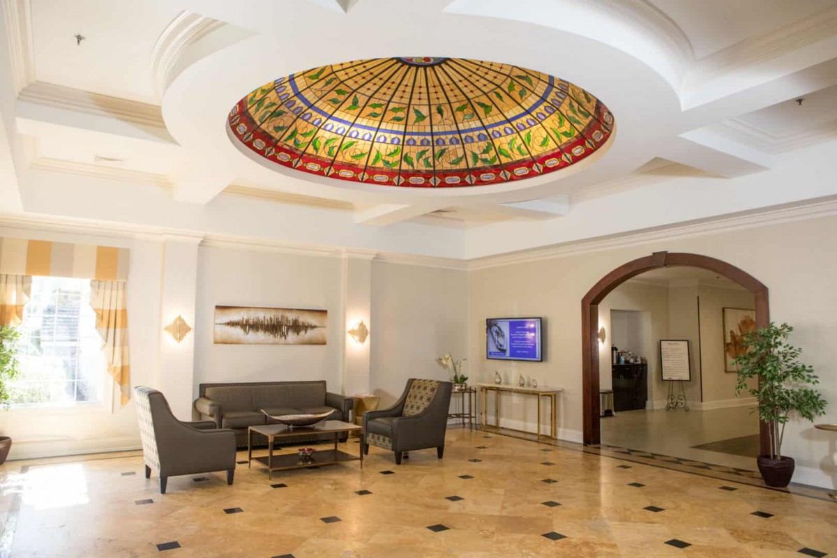 A spacious lobby featuring a stained glass dome ceiling and elegant seating arrangement.