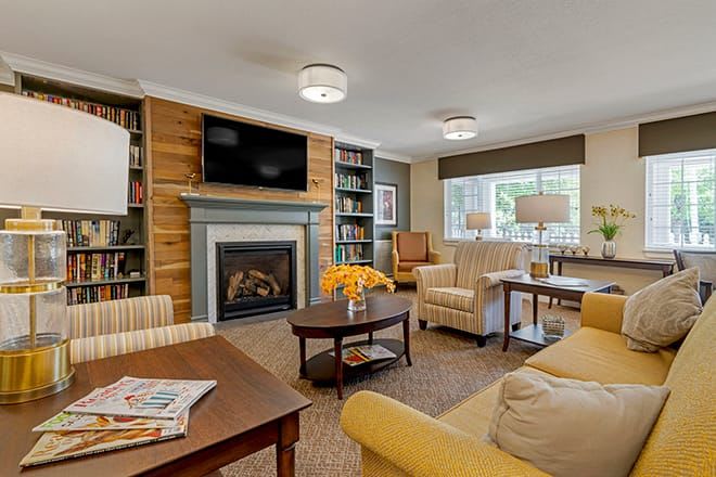 A cozy living room with comfortable seating, a fireplace, and bookshelves.