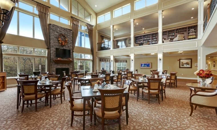 A spacious dining room with high ceilings, large windows, and elegant furnishings.