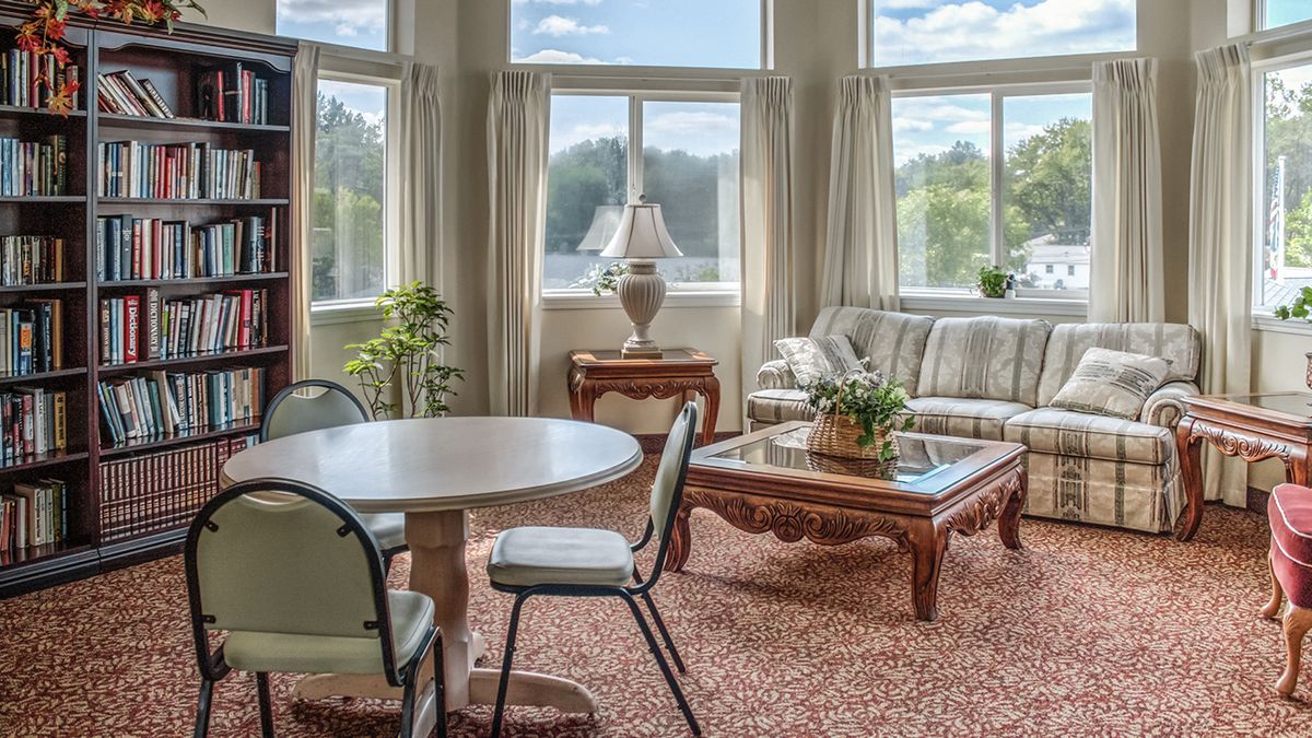 A cozy living room with large windows, a round table, and comfortable seating.