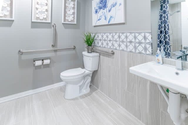 A modern bathroom featuring a toilet, sink, and decorative tiles.