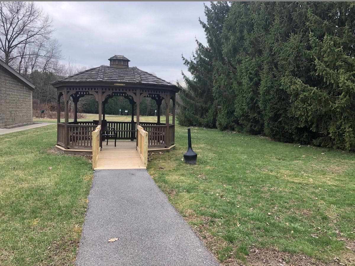 A scenic view of a gazebo in a park, surrounded by greenery and trees.