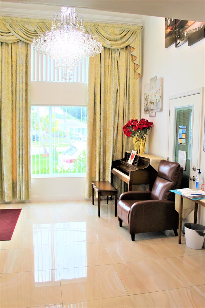 A cozy living room featuring a piano, armchair, and large windows with elegant curtains.