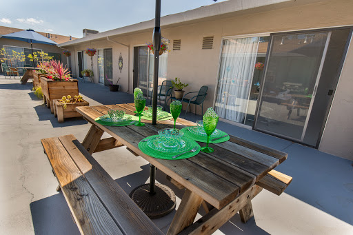 A beautifully arranged outdoor picnic table featuring vibrant green glass plates and cups, set in a cozy patio environment.