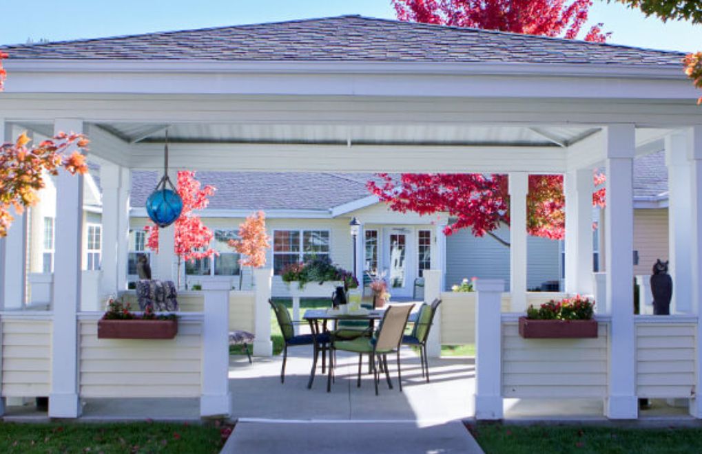 A cozy patio area featuring a table and chairs, surrounded by vibrant autumn foliage.
