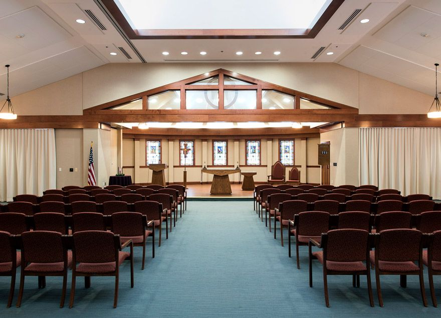An interior view of a synagogue featuring rows of seating and a raised pulpit area.