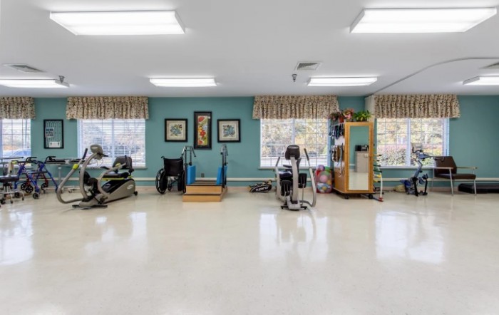 A spacious rehabilitation room equipped with various exercise machines and therapy tools.