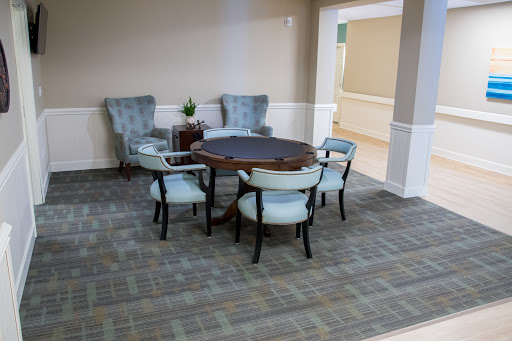 A cozy seating arrangement featuring a round table and four chairs, complemented by two armchairs in a welcoming interior space.