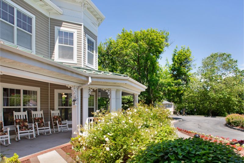 A charming house with a front porch and a lush garden on a sunny day.