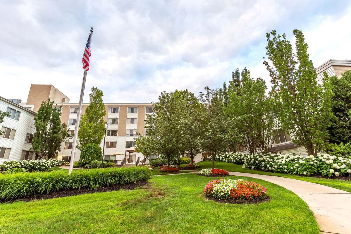 A well-landscaped area with a building in the background, featuring neatly arranged flowers and an American flag.