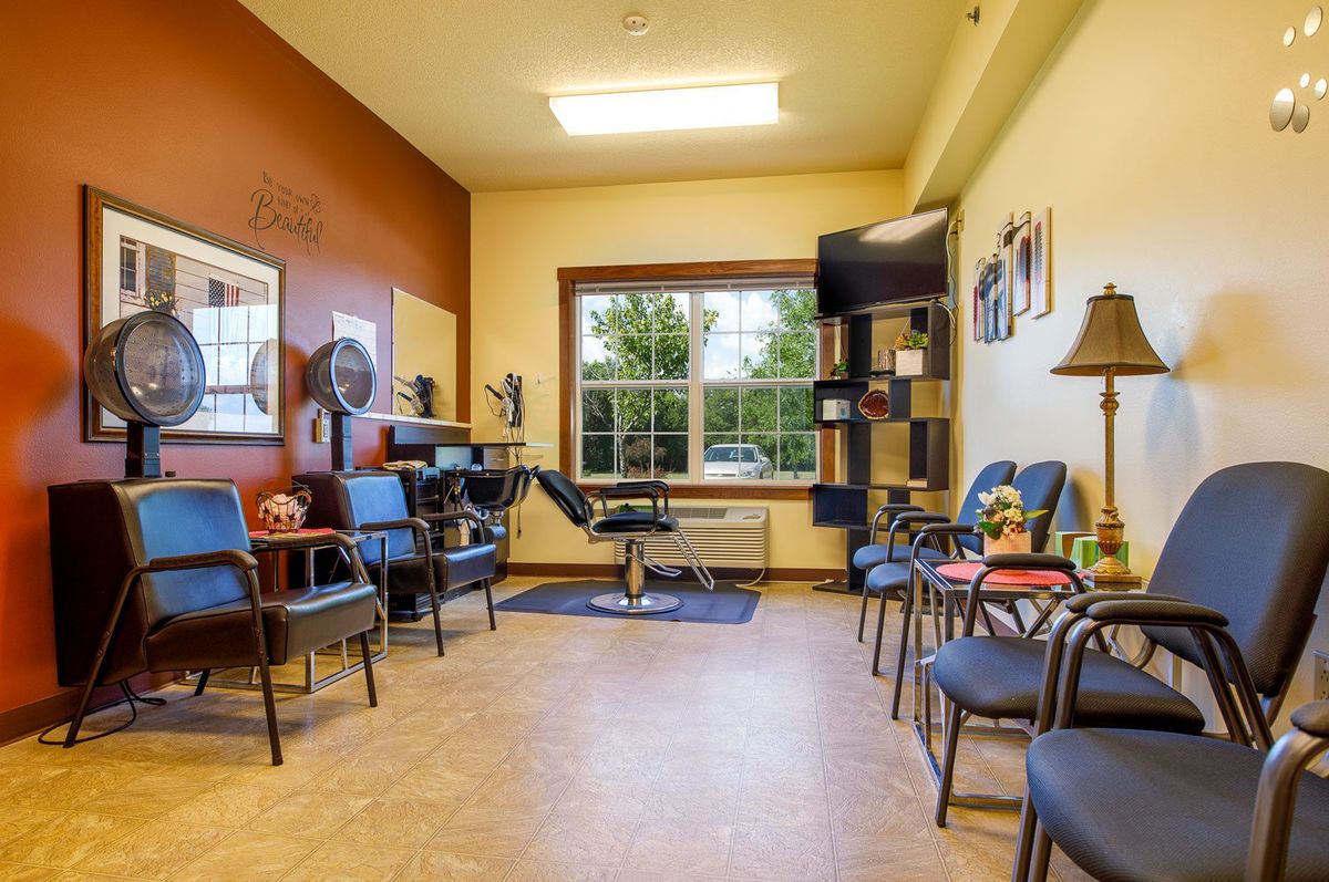 A cozy waiting room with several chairs, a television, and a window providing natural light.