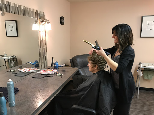 A hairstylist is curling a client's hair in a modern salon setting.