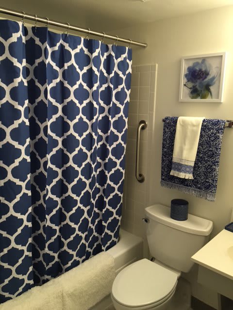 A bathroom with a blue and white patterned shower curtain and matching towels.