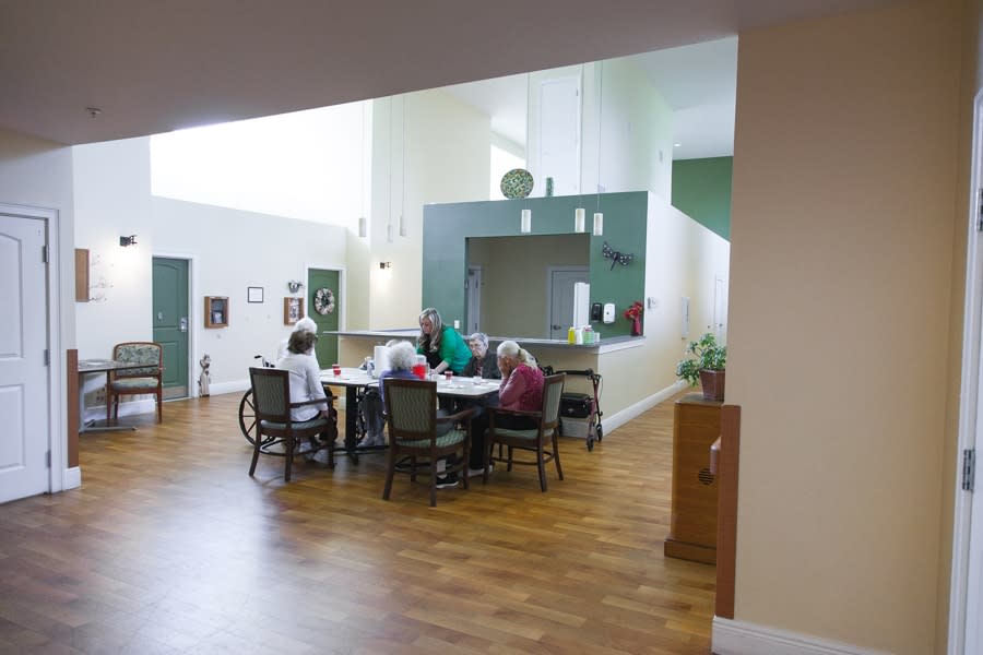 Elderly individuals gathered around a table in a communal seating area.
