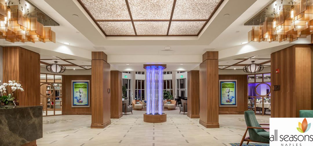 A spacious and modern lobby featuring wooden columns and a central lighting fixture.