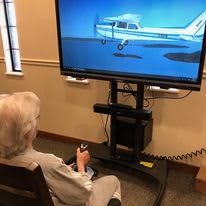 An elderly person using a flight simulator in an indoor setting.