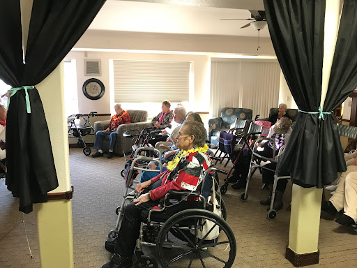 A group of elderly individuals seated in wheelchairs, participating in a social activity at an assisted living facility.