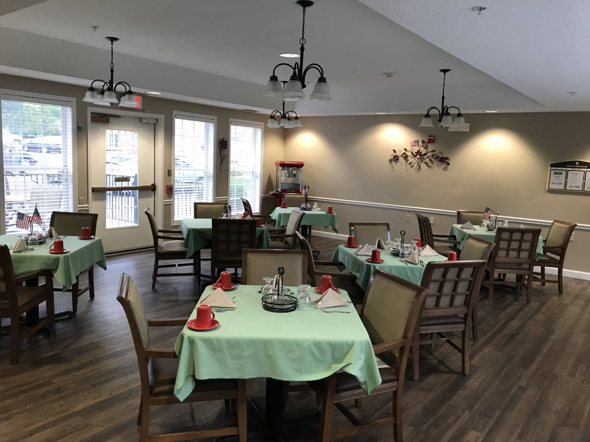 A cozy dining room with neatly arranged tables and chairs, featuring soft lighting and elegant decor.