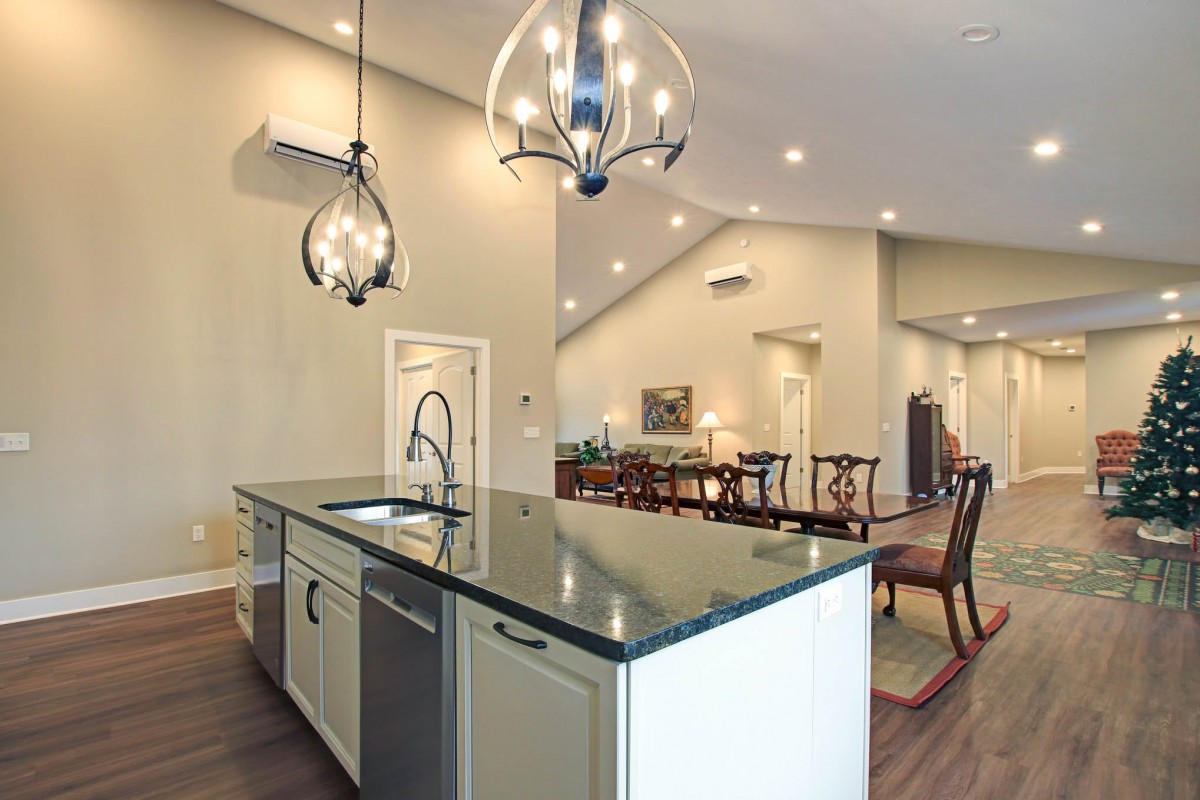 A modern kitchen with an island and open floor plan, featuring elegant chandeliers and a dining area.