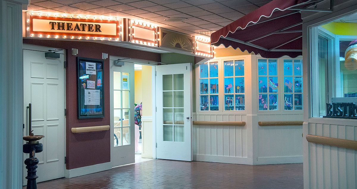 The entrance to a theater with bright marquee lights and posters on display.