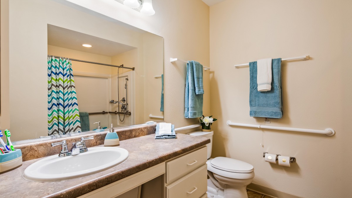 A well-organized bathroom with a sink, mirror, toilet, and shower area.