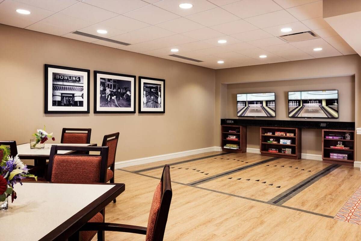 A modern game room with a shuffleboard table and seating area.