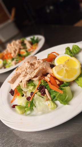 A fresh salad topped with tender chicken, garnished with lemon slices and colorful vegetables.