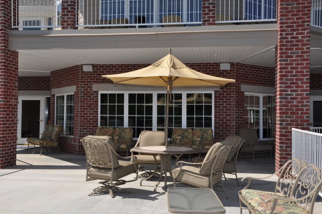 A cozy outdoor patio area featuring a table with an umbrella and seating, set against a brick building.