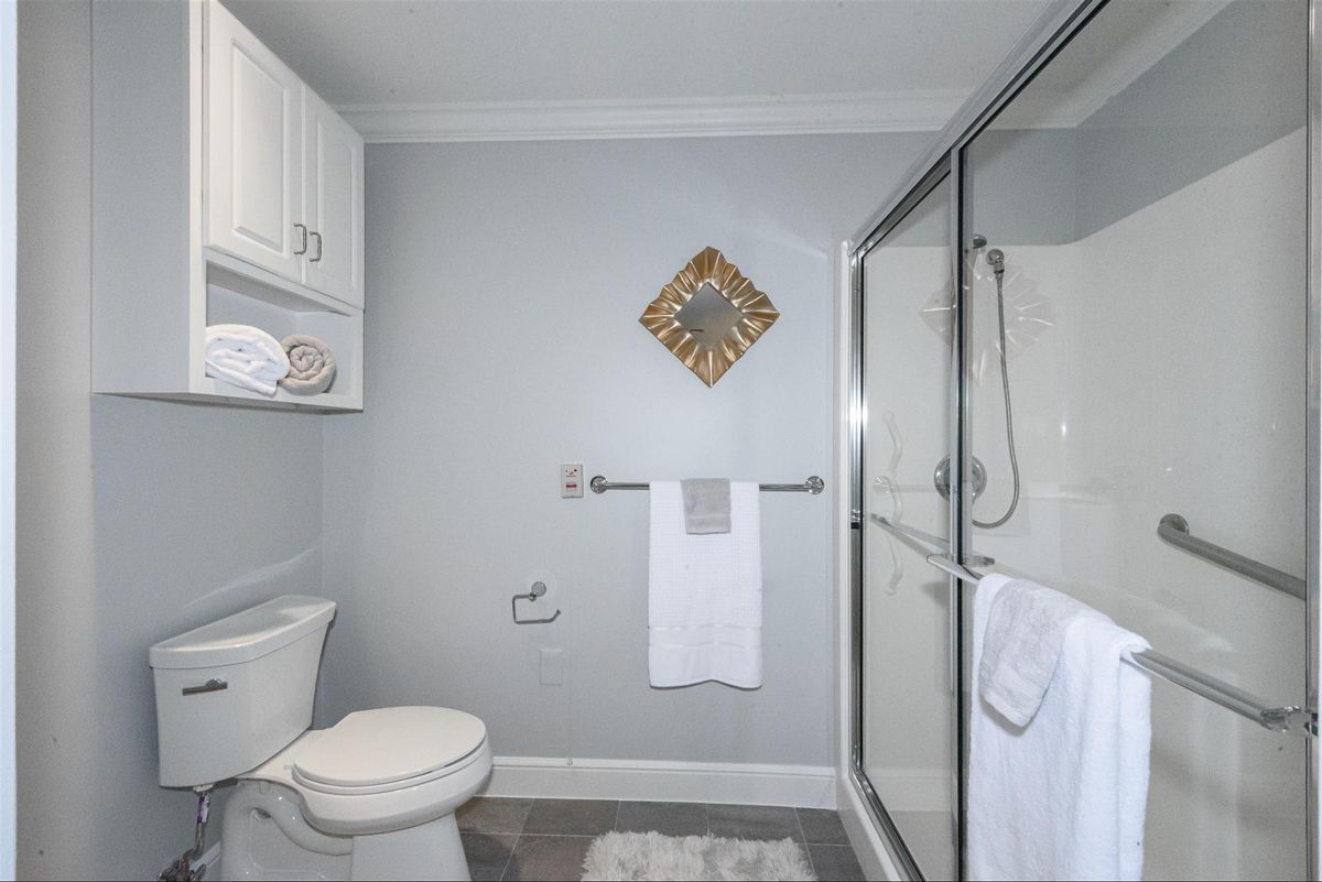A modern bathroom featuring a toilet, shower, and neatly arranged towels.