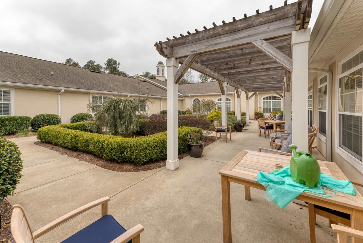 A serene outdoor patio with a pergola, surrounded by lush garden landscaping.