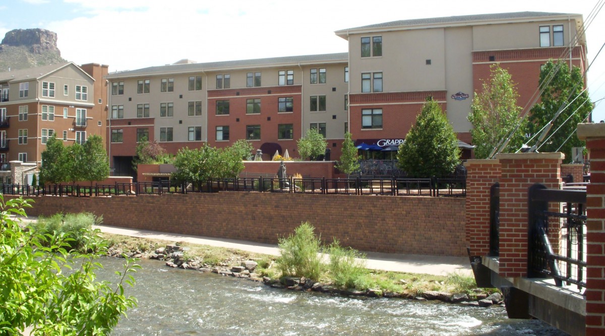 A riverside apartment building with trees lining the waterfront.