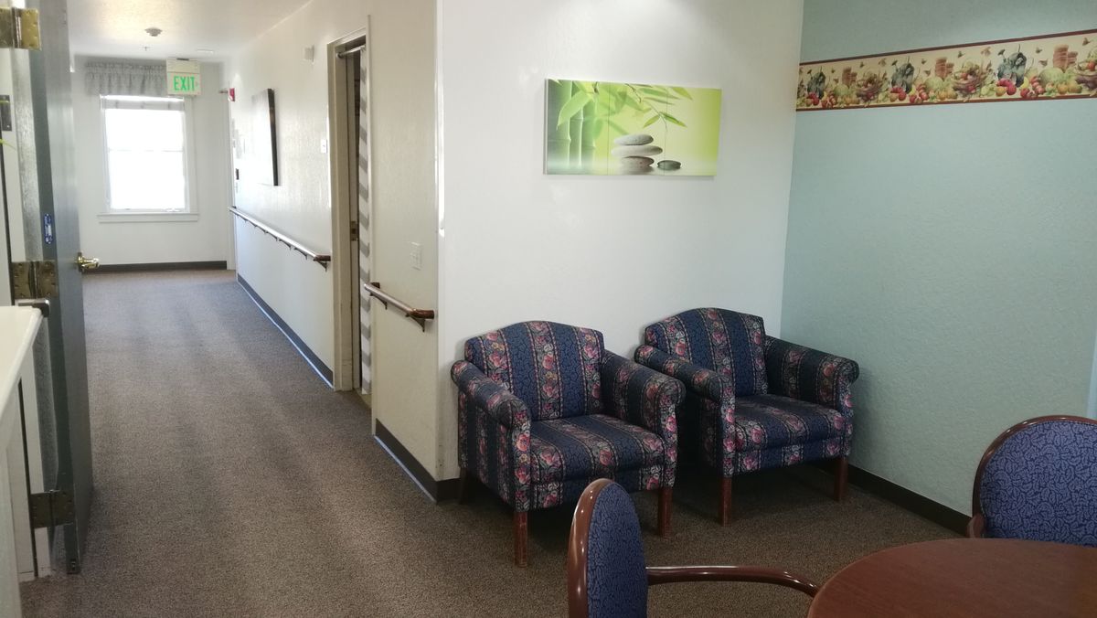 A small waiting area with two patterned chairs and a painting on the wall, located in a hallway.