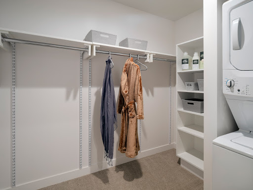 A well-organized closet featuring hanging clothes and neatly arranged shelving.