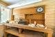 A rustic kitchen with wooden shelves and a clock on the wall.