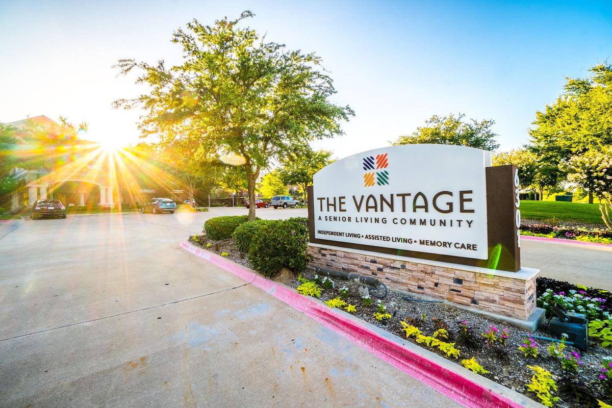 Entrance sign of The Vantage apartment community, surrounded by landscaping and illuminated by sunlight.