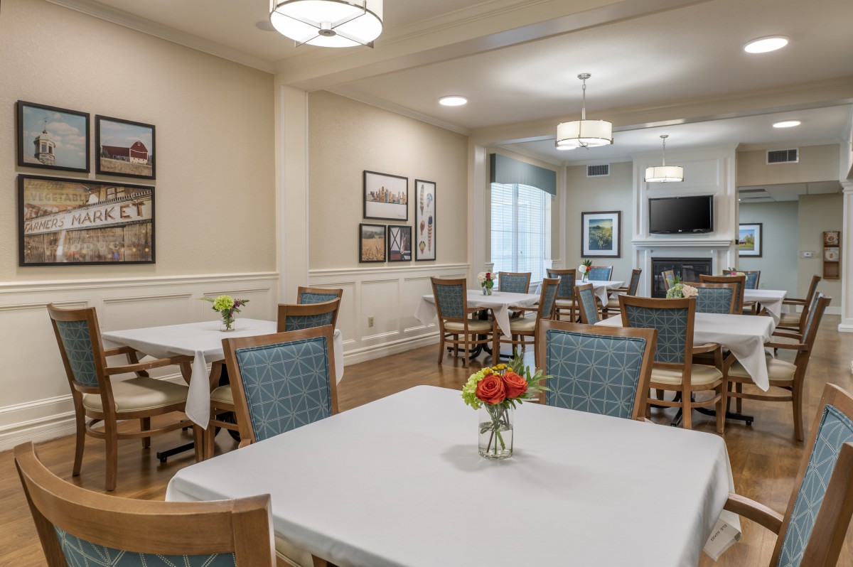 A well-lit dining room with neatly arranged tables and chairs, featuring tasteful decor and floral centerpieces.