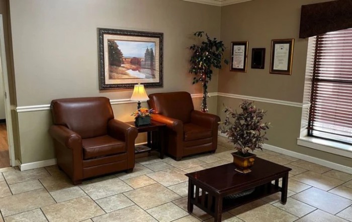 A cozy and well-decorated waiting room with leather chairs, a coffee table, and artwork on the wall.