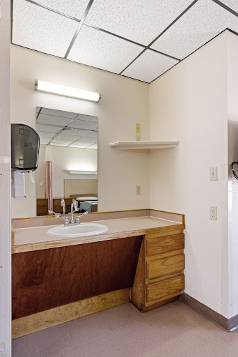 A simple and functional bathroom setup featuring a sink, mirror, and wooden cabinetry.