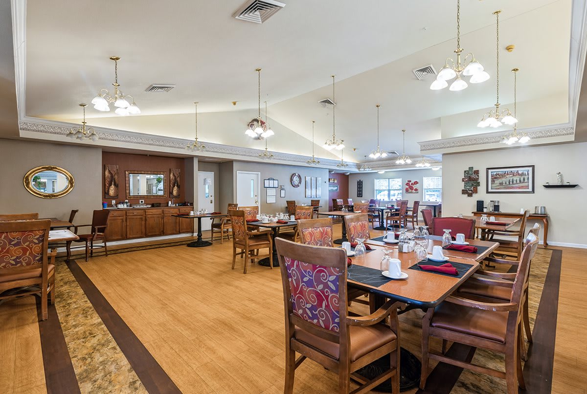 A spacious and elegantly decorated dining room with wooden floors, tables, and chairs.