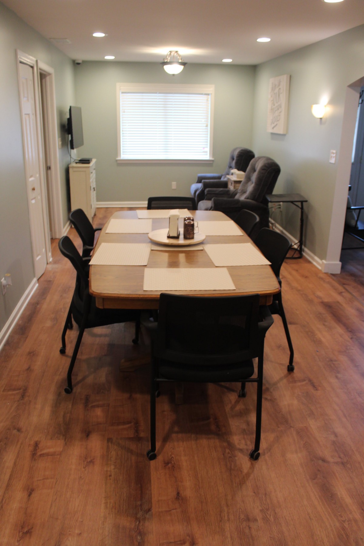 A dining room with a wooden table and chairs, featuring a wooden floor and a window.