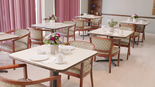 A serene and elegantly arranged dining area, featuring neatly set tables and decorative flowers.