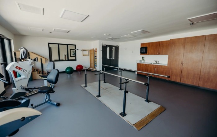 A rehabilitation room equipped with parallel bars and exercise tools.