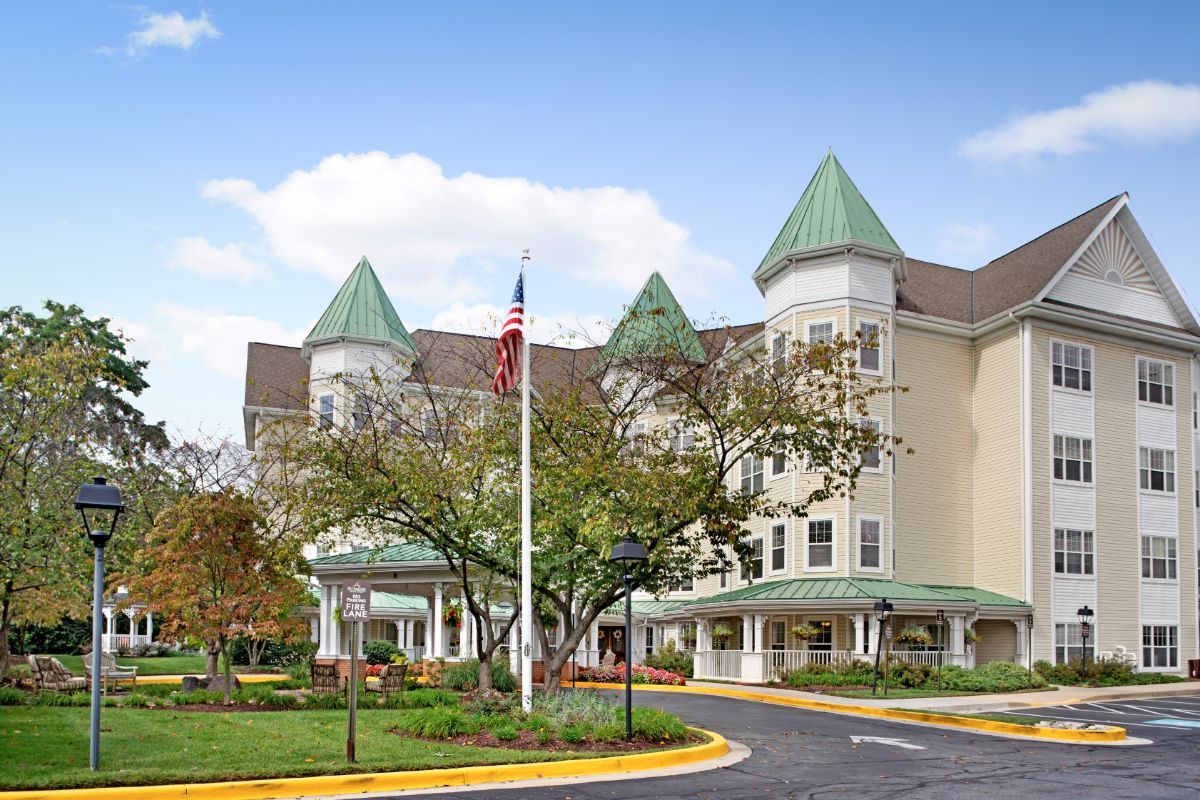 A large, elegant building with green conical roofs, surrounded by trees and featuring an American flag in front.